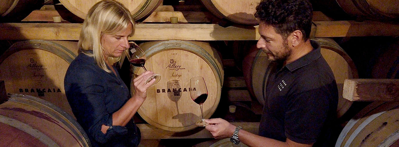 Frau und Mann degustieren Wein neben Weinfass – Casa Brancaia-Weine online kaufen bei Vinothek Brancaia